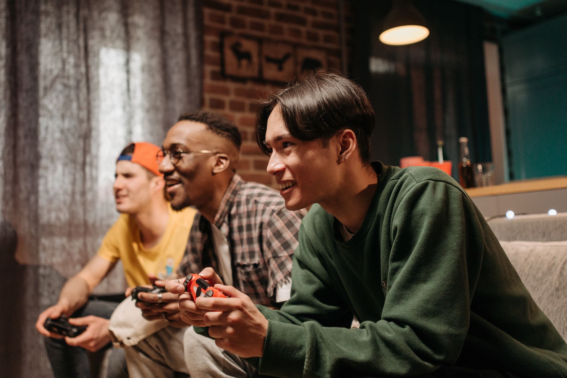 Three friends playing games together on a sofa